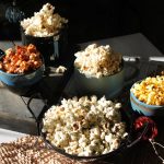 Assorted bowls of gourmet popcorn in a rustic, cozy setting, perfect for a snack lover.